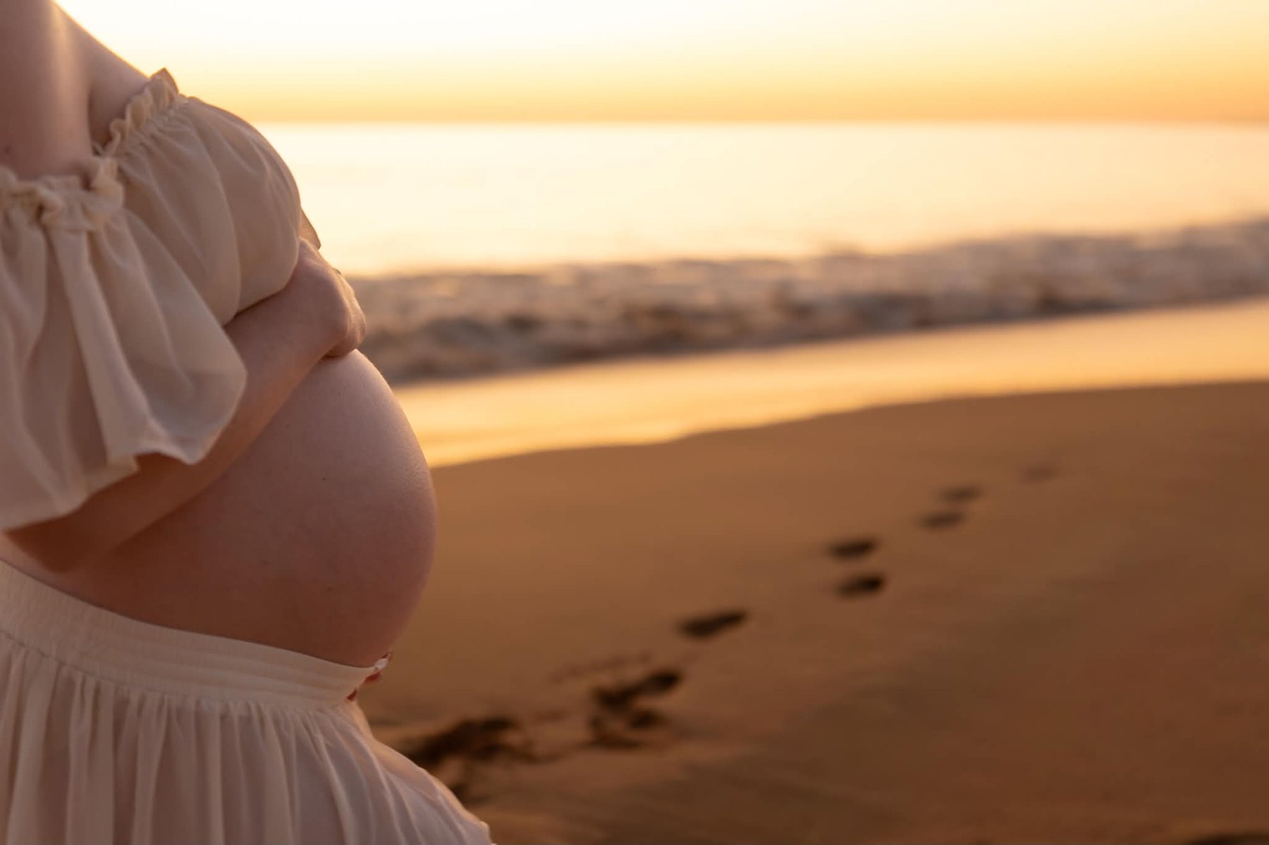 Maternity photography, close-up of bump at sunset on the beach, Western Sydney